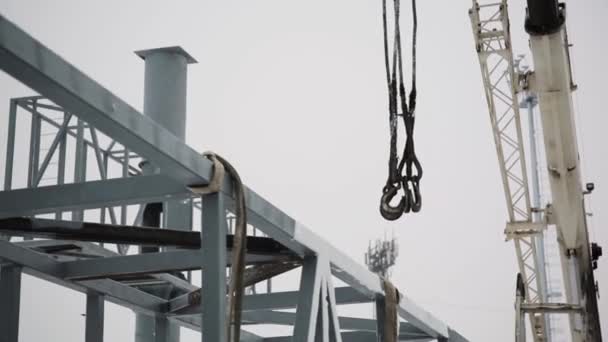 Crane is used in the construction of buildings. construction crane equipment over building construction site and take worker to high site on day. Construction site background - Footage, Video