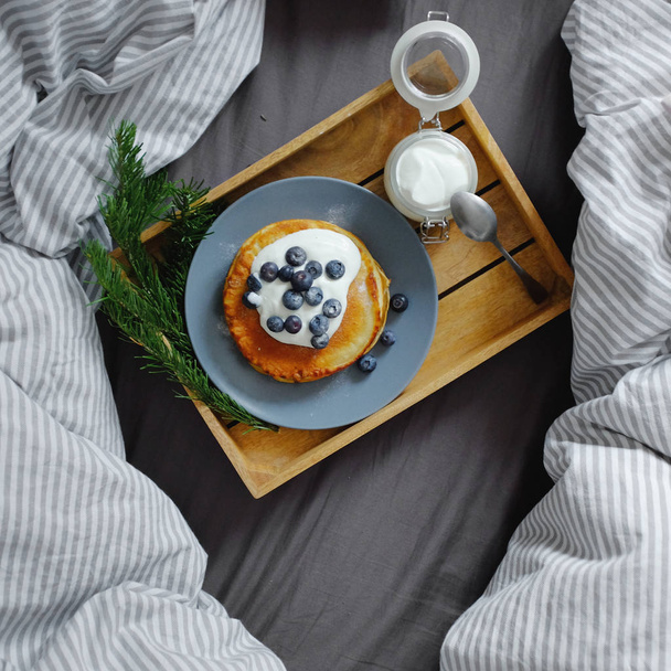 Pancakes with sour cream and blueberries on a tray - Fotó, kép