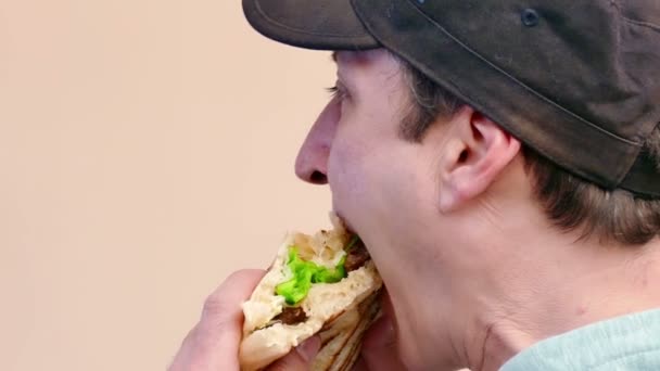 Mladý muž je jí šťavnatý hamburger s vepřové a zelený salát, 4k Video klip - Záběry, video