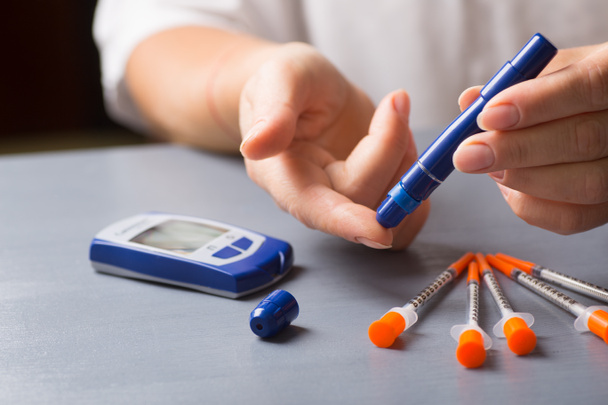 女性ホーム glucometer と注射器のペンを使って血糖値をチェック. - 写真・画像