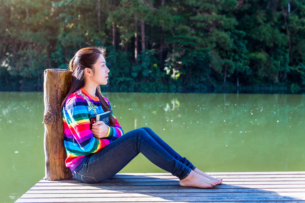 Young girl sitting on a pier. - Zdjęcie, obraz