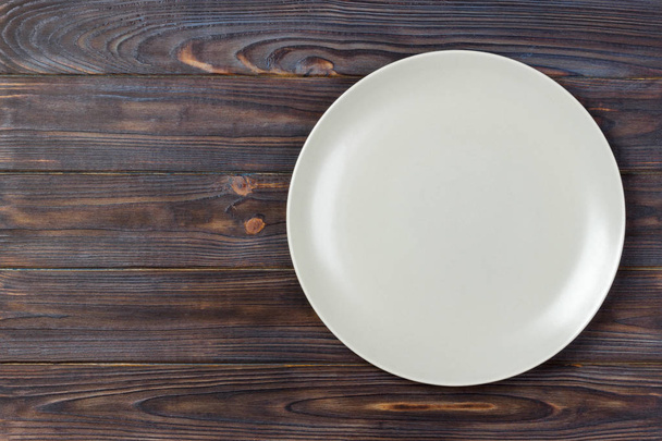 Вид сверху на пустую матовую тарелку на ржавом деревянном столе. Вид сверху
 - Фото, изображение