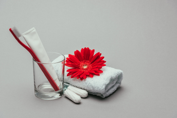 close up view of hygiene supplies, flower and towel isolated on grey - Foto, Imagen