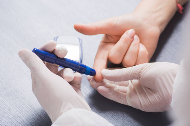 Doctor's hand in medical latex glove checking patient's blood glucose level using syringe pen - 写真・画像
