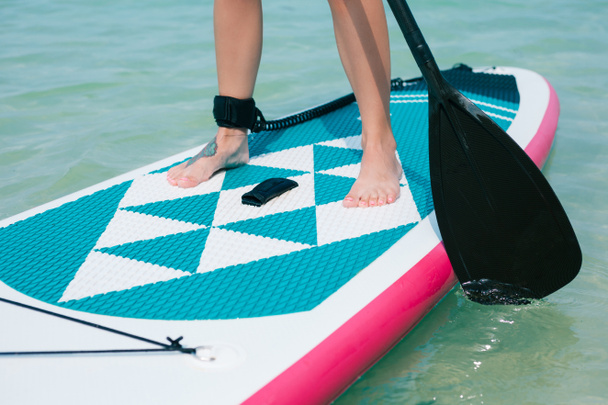 visão de seção baixa da mulher em stand up paddle board no mar no resort tropical
 - Foto, Imagem