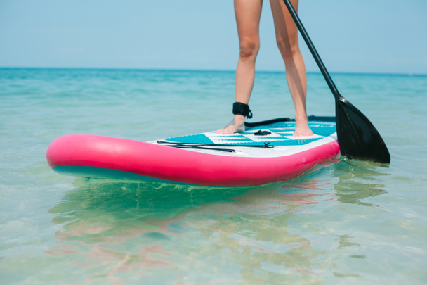 bijgesneden beeld van de vrouw op stand up paddle board op zee  - Foto, afbeelding