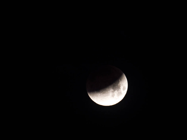 Fotografía de cerca del raro eclipse lunar total de luna llena de sangre azul sobre Chicago en la mañana del 31 de enero de 2018 mientras perece entre nubes en el oscuro cielo nocturno antes del amanecer
. - Foto, imagen