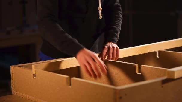 lähikuva miehen kädestä, joka työntää levyn lastulevyyn
 - Materiaali, video