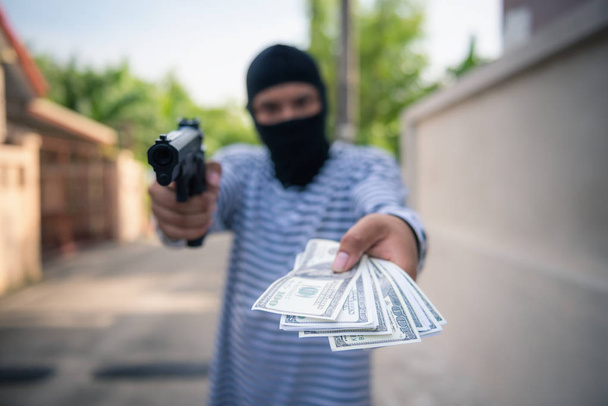強盗の銃が被害者からお金を取ることを目指して  - 写真・画像