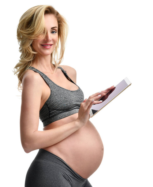 Beautiful pregnant woman with big belly use pregnancy motherhood expectation application typing on digital tablet pad  - Foto, afbeelding