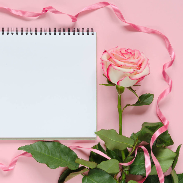 Pink blooming fresh rose flower and notebook on pink background - Zdjęcie, obraz