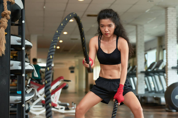 Asian young woman concentrated on battle rope exercise - Photo, Image