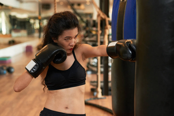 Asiatico giovane donna colpire punching bag a training in gym
 - Foto, immagini