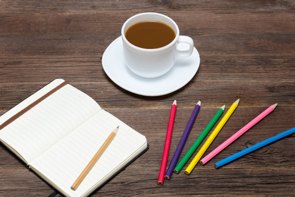 Кавовий кухоль, кольорові олівці та блокнот. Дерев'яний фон
 - Фото, зображення