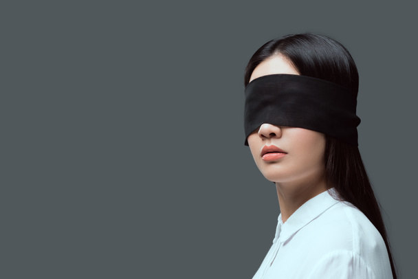 junge Frau mit schwarzen Augenbinde isoliert auf grau - Foto, Bild