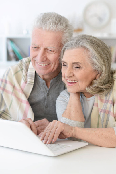 portrait of happy beautiful senior couple with blanket using laptop at home - Photo, image