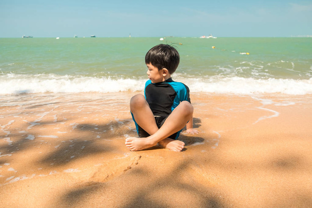 Мальчик в купальнике сидит на пляже и играет в песок
  - Фото, изображение