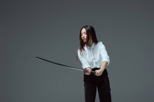beautiful asian girl holding katana sword isolated on grey - Foto, Imagem