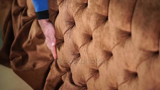 lähikuva miehen kädestä, joka koskettaa pehmeää liinaa sohvalta
 - Materiaali, video