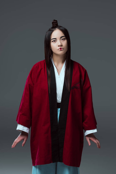 beautiful young asian woman in kimono looking at camera isolated on grey - Foto, afbeelding