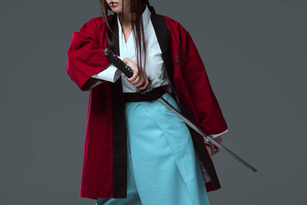 обрезанный снимок самурая в кимоно, держащего меч катаны изолированный на сером
 - Фото, изображение