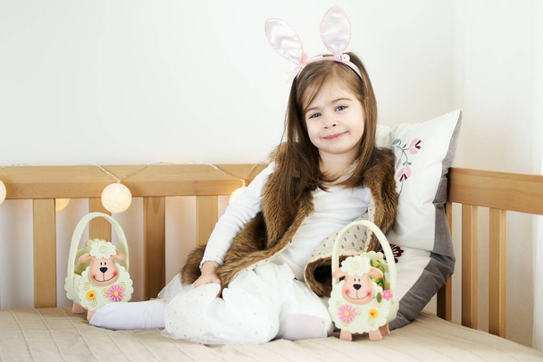 маленькі дівчата в кролячих вухах сидять на дивані з великодніми кошиками
 - Фото, зображення