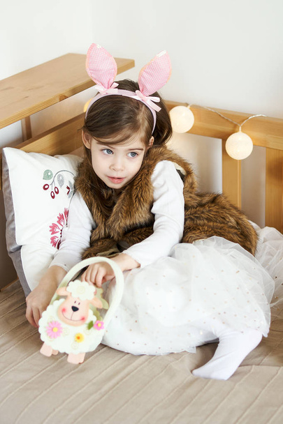 Kleines Mädchen in Hasenohren sitzt mit Osterkörben auf der Couch - Foto, Bild