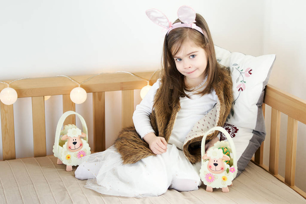 niñas en orejas de conejo se sientan en el sofá con cestas de Pascua
 - Foto, imagen