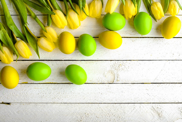 Spring easter eggs on wooden background, eggs and tulips on table, overhead - Foto, Imagen