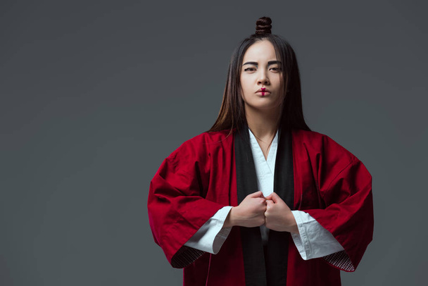 serious asian woman in traditional japanese kimono looking at camera isolated on grey - Foto, imagen