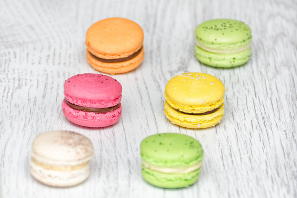 Six multicolored macarons on a light wooden table - 写真・画像