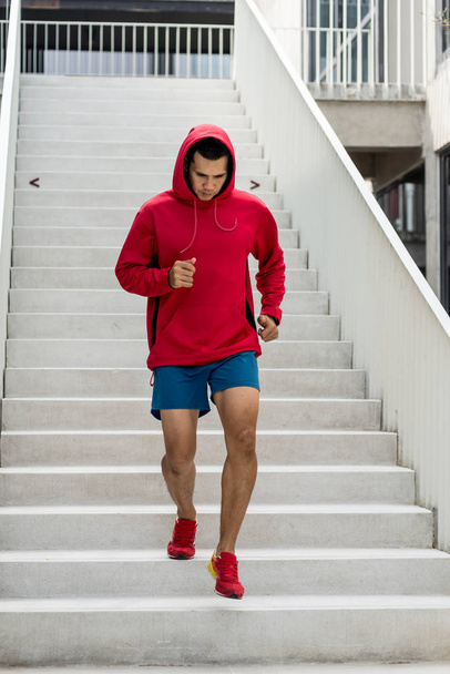 Sport man in red hood running down at steps, motion blur. - Fotoğraf, Görsel