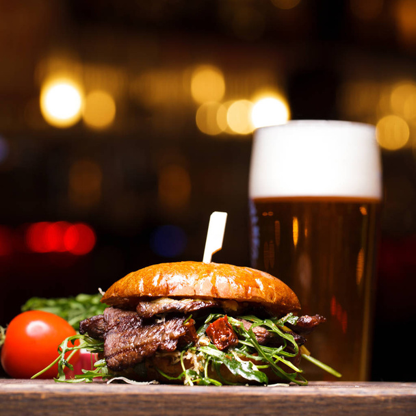Hamburger from beef and a glass of light beer - Фото, изображение