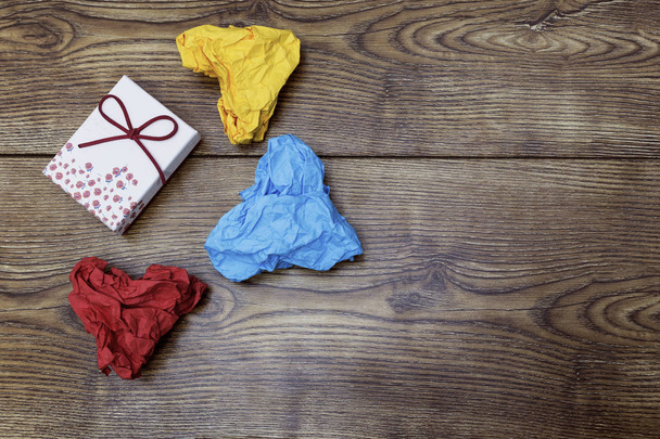 Une boîte-cadeau et trois papiers froissés en forme de coeur coloré sur une table en bois. La Saint-Valentin. Jour de l'Amant
. - Photo, image