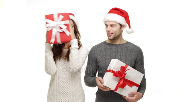 4k young couple playing and hiding behind Christmas present box on white isolated background. - Video