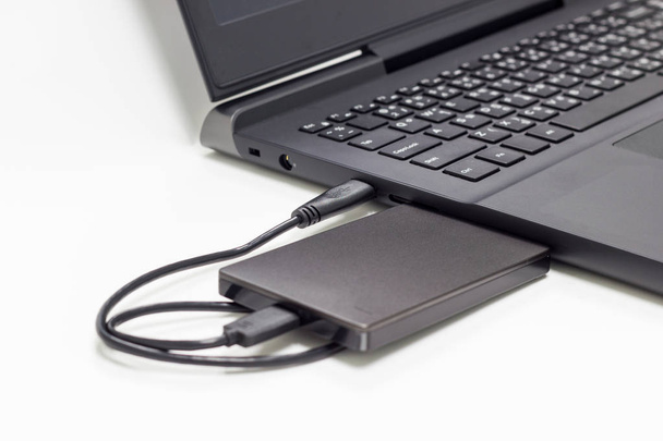 zwarte externe harde schijf verbinden met laptop computer geïsoleerd witte achtergrond  - Foto, afbeelding