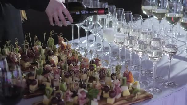 The waiter pours the champagne into the glasses. Table top full of glasses of sparkling white wine with bottles in the background. - Footage, Video