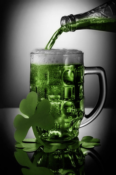 Unusual green beer poured into glass in front of light spot. St. Patrick Day concept. - Foto, immagini