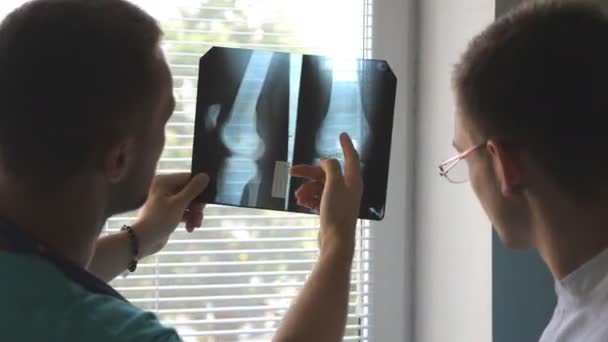 İki erkek doktor MRI resim ve bu konuda tartışmaya görüntüleyin. Tıbbi işçi arıyor ve x-ışını parmak analiz hastanede. Doktor birbirleri ile başvurun. Arka arka görünümü kapatın - Video, Çekim