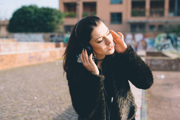 молодая красивая женщина слушает музыку на открытом воздухе со смартфоном
  - Фото, изображение