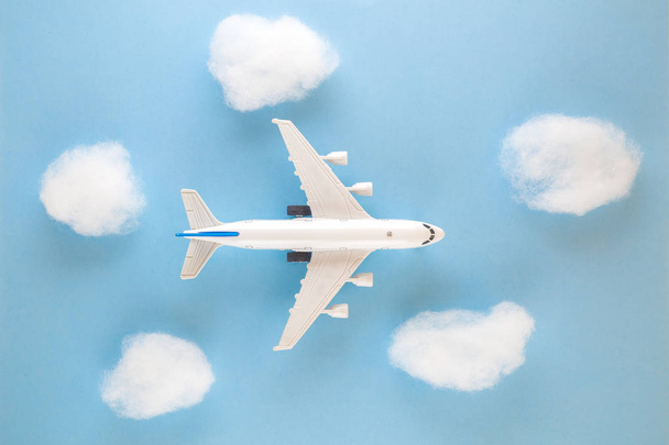 High angle view of airplane toy and clouds on blue sky background - Foto, afbeelding