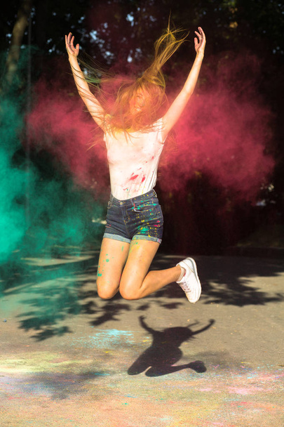 Pozitif sarışın kadın arou patlayan canlı renklerle atlama - Fotoğraf, Görsel