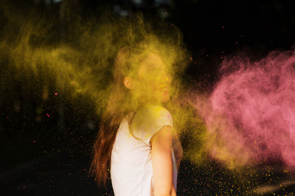 Charming young woman having fun in a cloud of yellow and pink dr - Foto, Imagem