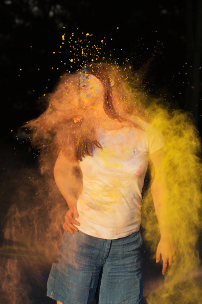Θετική μελαχρινή μοντέλο καλύπτεται με κίτρινη σκόνη γιορτάζει H - Φωτογραφία, εικόνα