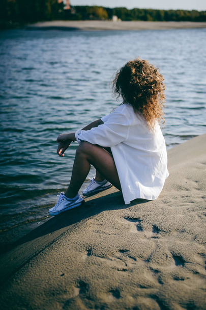 lovely young woman with curly hair, the romance of youth, a journey walk on a warm summer sunny day on a sandy beach with water - Fotoğraf, Görsel