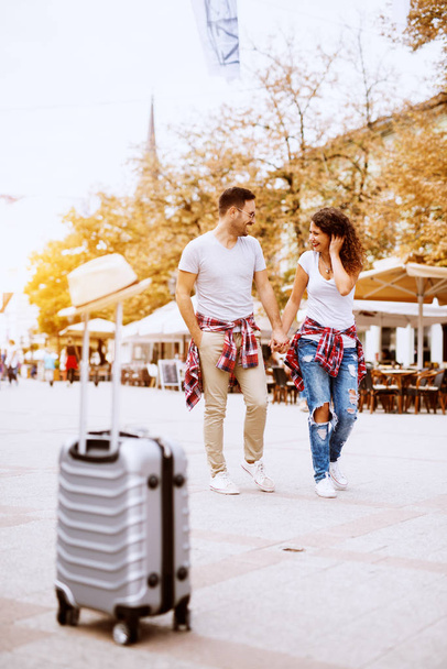 jeune couple amoureux heureux voyageant dans la ville, valise au premier plan
 - Photo, image