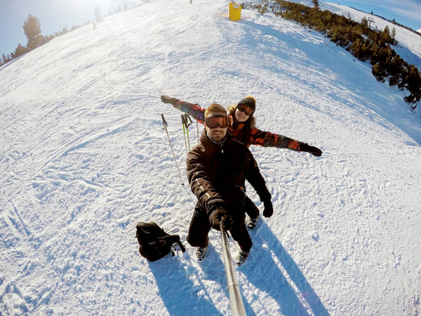 mladá žena a muž v zimních horách lyžování a s selfie - Fotografie, Obrázek