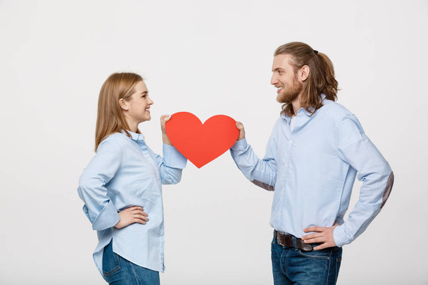 Portrét mladého šťastný pár v lásce drží červené papírové srdce. - Fotografie, Obrázek