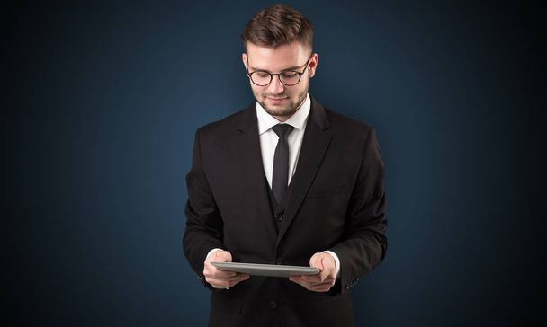 Businessman holding tablet with dark background - Foto, afbeelding
