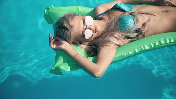 Young pretty woman lying on air mattress in the swimming pool - Photo, Image